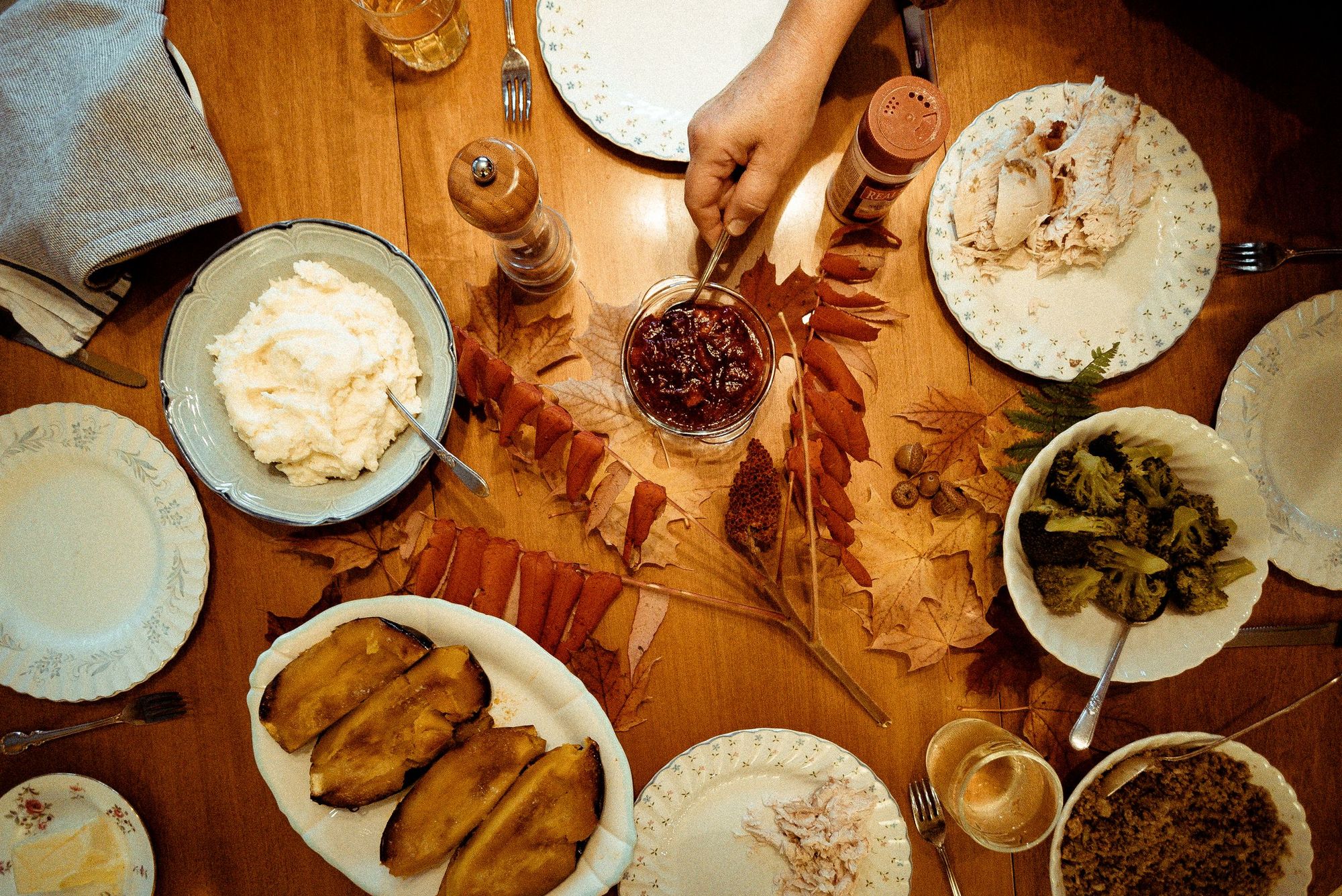 Gedeckter Herbsttisch von oben mit Süßkartoffeln, Püree, Gemüse und Herbstlaub
